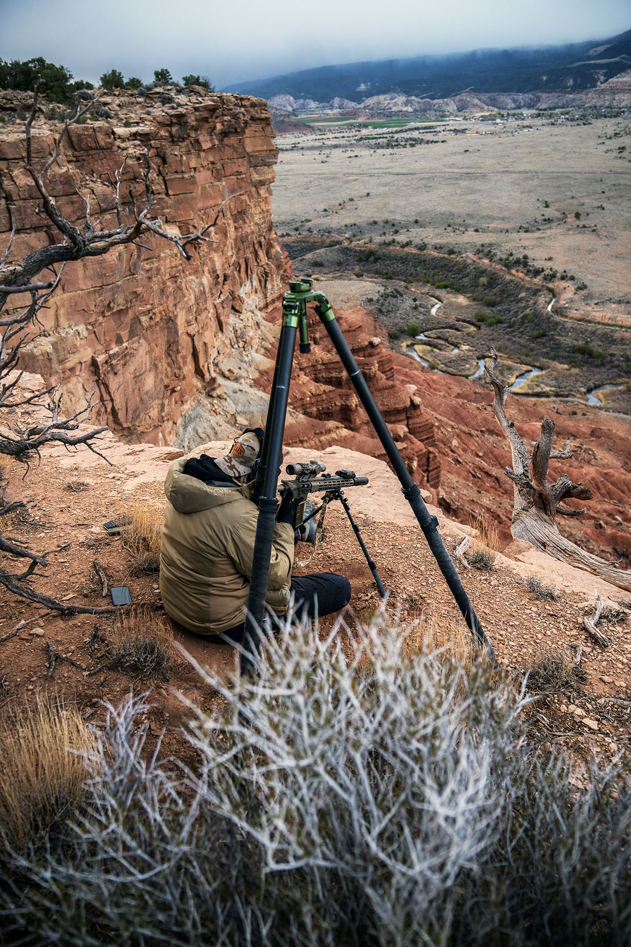 Tactical marksman scanning a canyon from a cliff edge during Buck Doyle scoped carbine training.